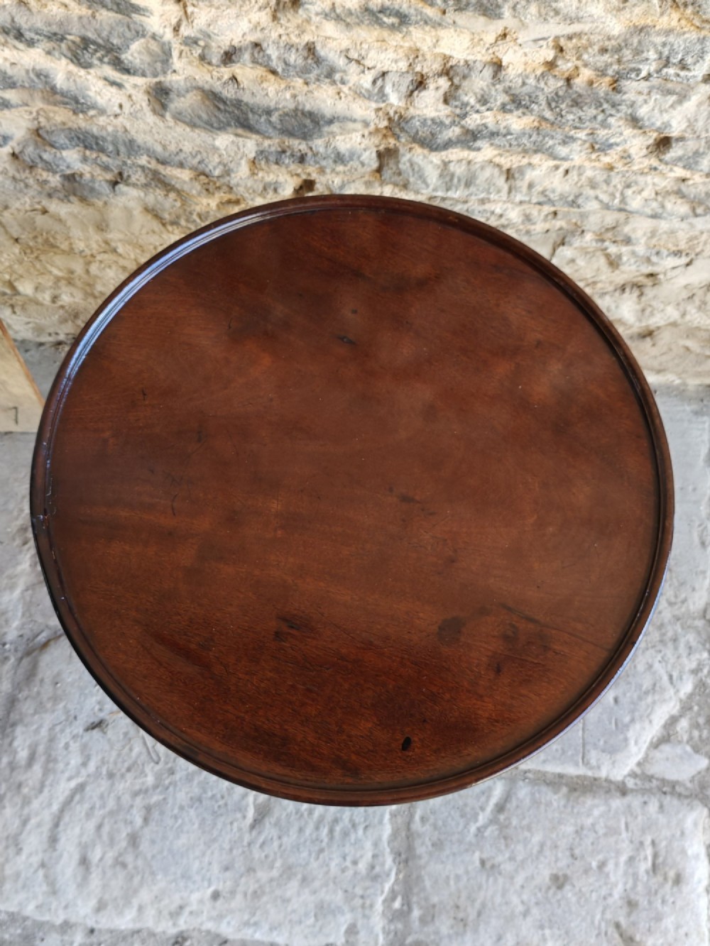A Regency period dark mahogany and rosewood circular dish top occasional table resting on a carved pedestal stem and a triform base. View III