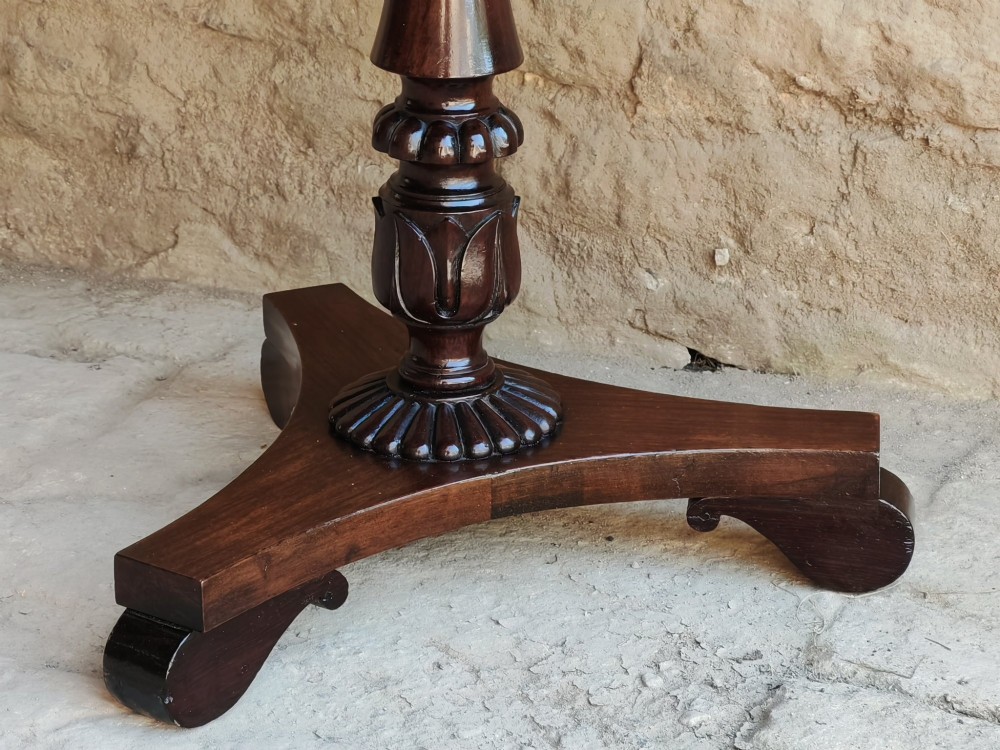 A Regency period dark mahogany and rosewood circular dish top occasional table resting on a carved pedestal stem and a triform base. View IV