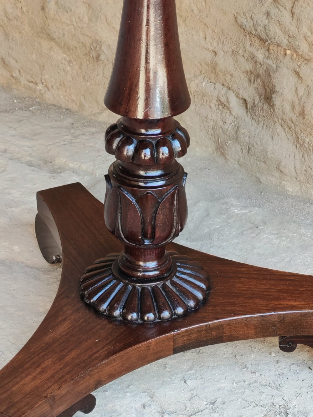 A Regency period dark mahogany and rosewood circular dish top occasional table resting on a carved pedestal stem and a triform base. View VI