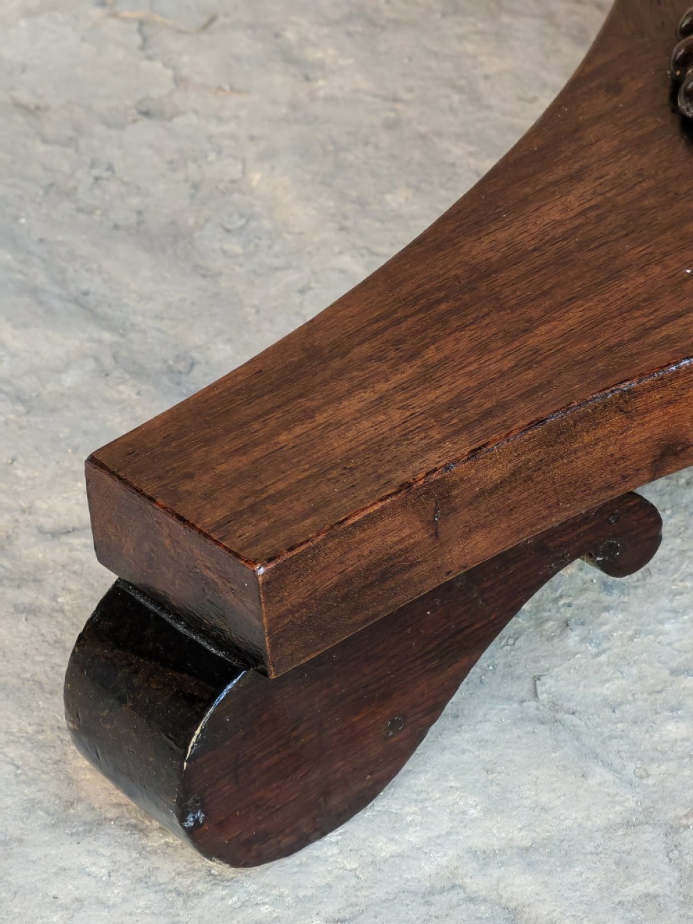 A Regency period dark mahogany and rosewood circular dish top occasional table resting on a carved pedestal stem and a triform base. View VII