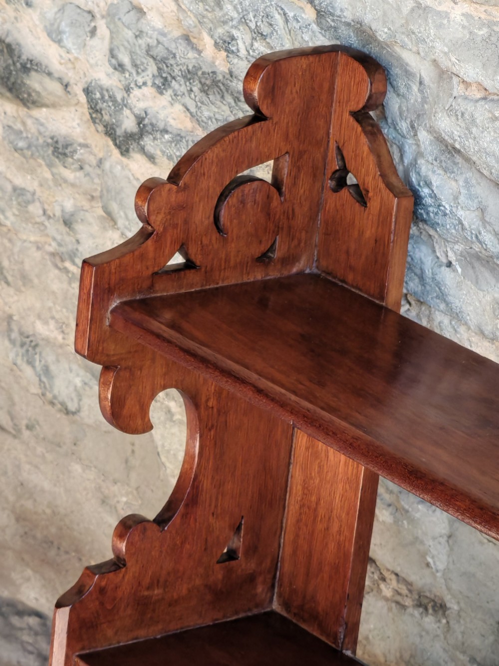 A late 19th-century warm brown walnut wall cabinet featuring pierced fretwork side panels, an upper display shelf, and twin mirrored doors at the base. View VI
