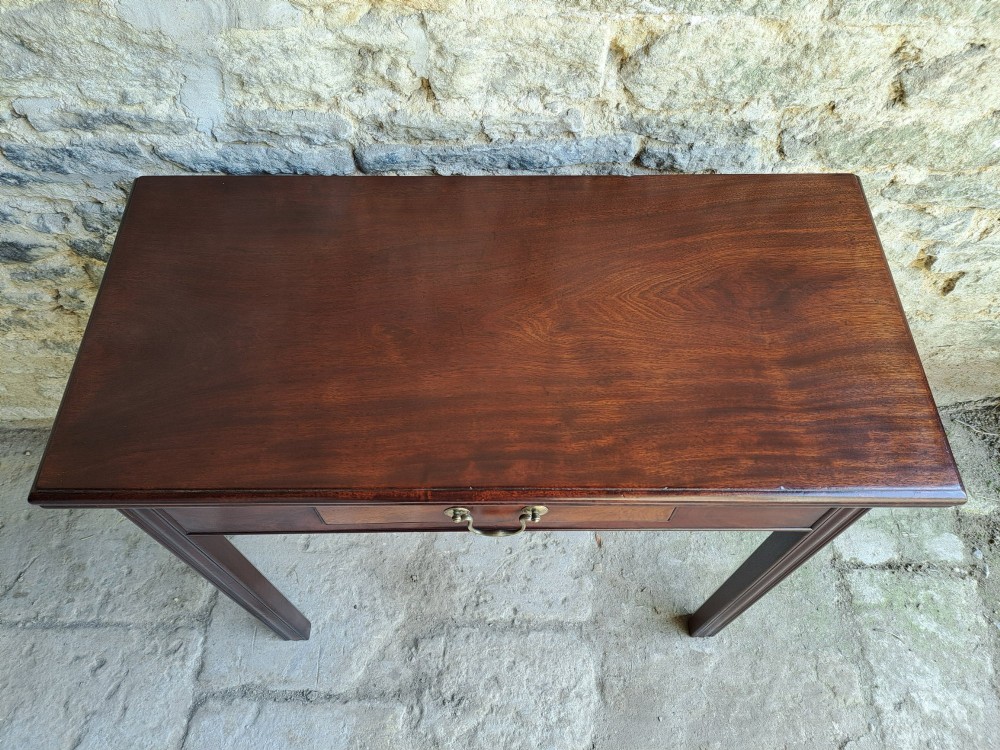 An 18th-century Georgian Cuban mahogany tea table featuring a rectangular foldover top, a single drawer with a brass handle, and straight moulded legs. View IV