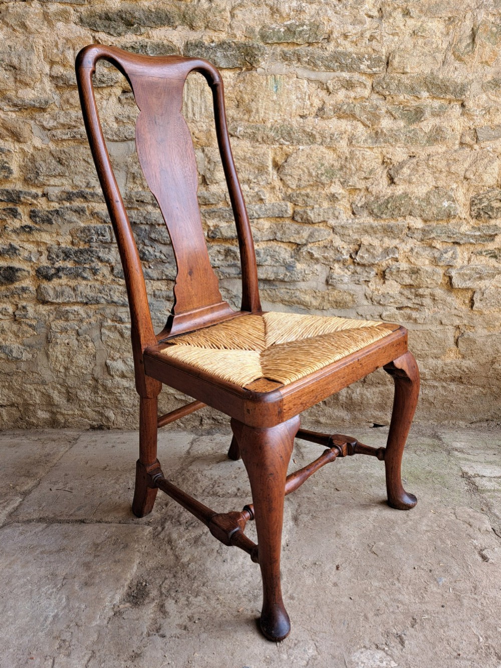 A Queen Anne walnut side chair featuring a solid vase-shaped back splat, a woven rush seat, cabriole front legs with pad feet, and turned stretchers. View II