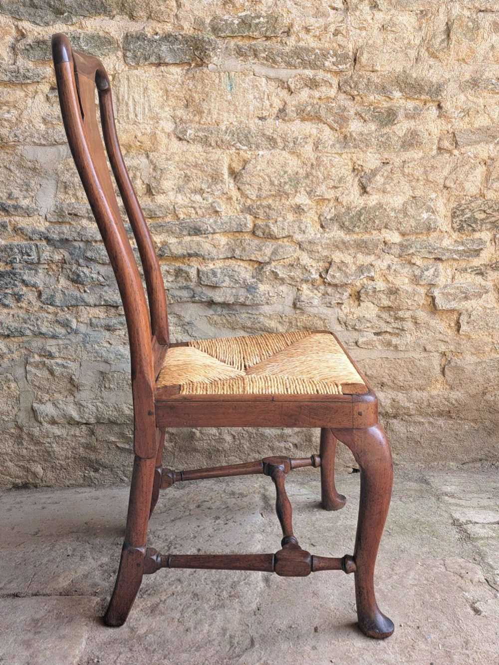 A Queen Anne walnut side chair featuring a solid vase-shaped back splat, a woven rush seat, cabriole front legs with pad feet, and turned stretchers. View III