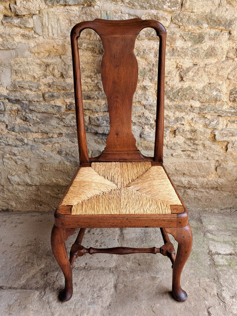A Queen Anne walnut side chair featuring a solid vase-shaped back splat, a woven rush seat, cabriole front legs with pad feet, and turned stretchers. View IV