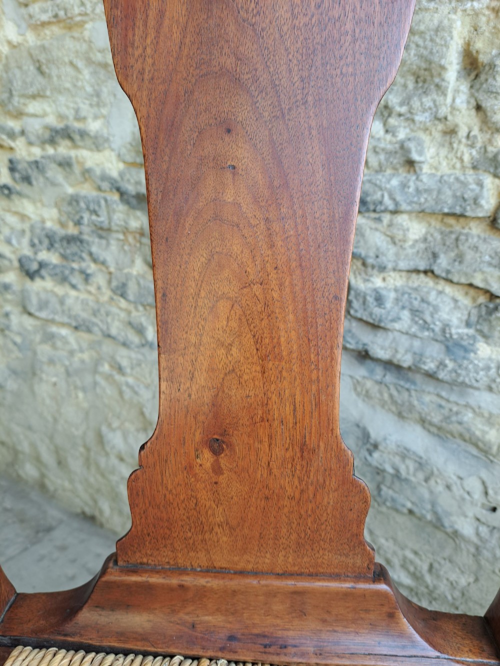 A Queen Anne walnut side chair featuring a solid vase-shaped back splat, a woven rush seat, cabriole front legs with pad feet, and turned stretchers. View VI