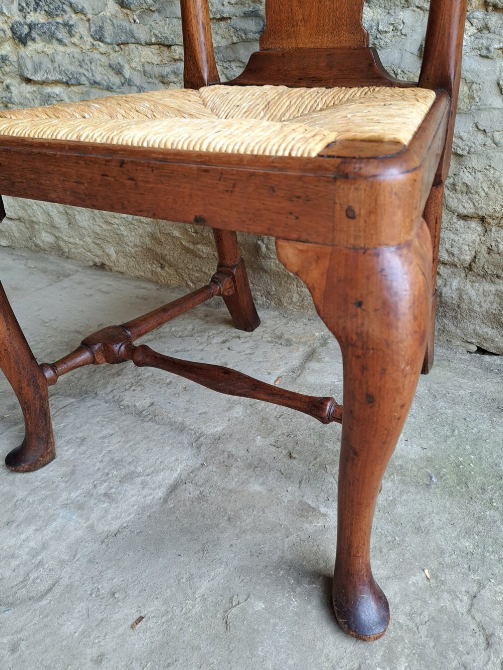 A Queen Anne walnut side chair featuring a solid vase-shaped back splat, a woven rush seat, cabriole front legs with pad feet, and turned stretchers. View VII