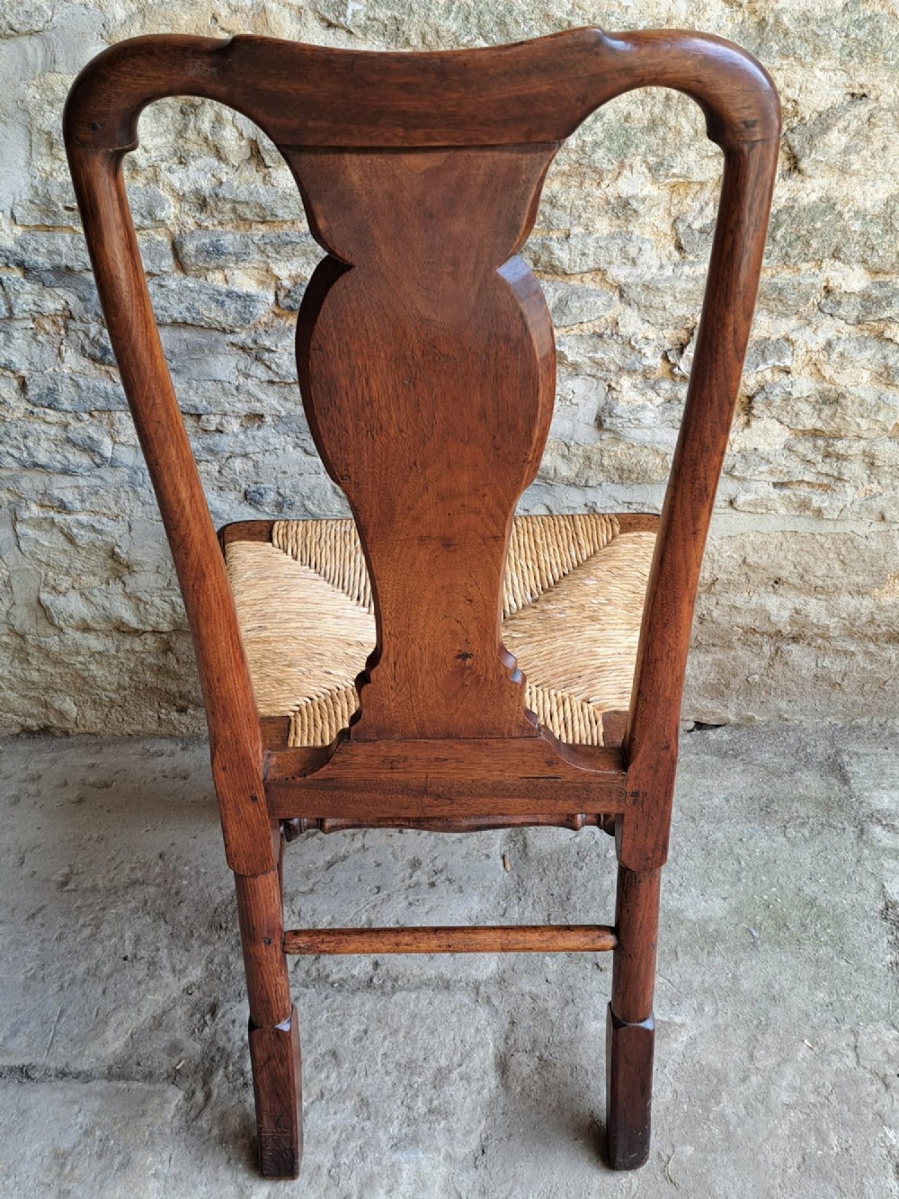 A Queen Anne walnut side chair featuring a solid vase-shaped back splat, a woven rush seat, cabriole front legs with pad feet, and turned stretchers. View IX