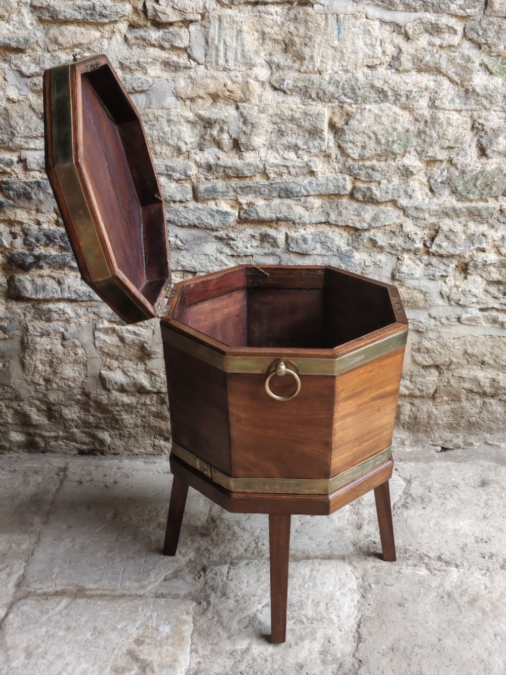 An 18th-century octagonal mahogany wine cooler with brass bindings, brass handles, and four tapered square legs. View V