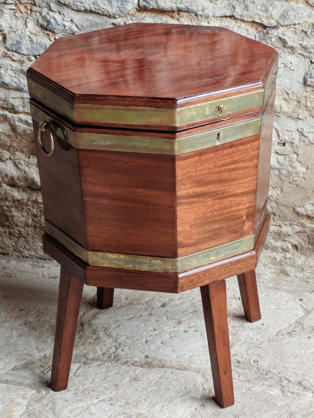 An 18th-century octagonal mahogany wine cooler with brass bindings, brass handles, and four tapered square legs. View VI