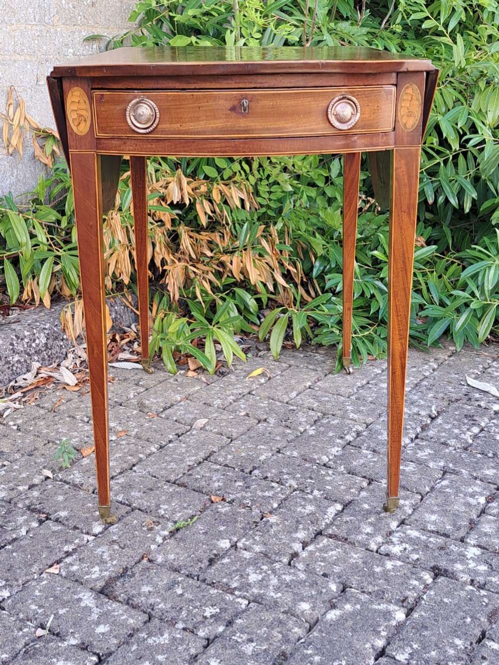 A George III mahogany drop-leaf Pembroke table featuring an oval satinwood shell inlay medallion, drawer with brass ring handles, and square tapered legs on brass castors. View IV