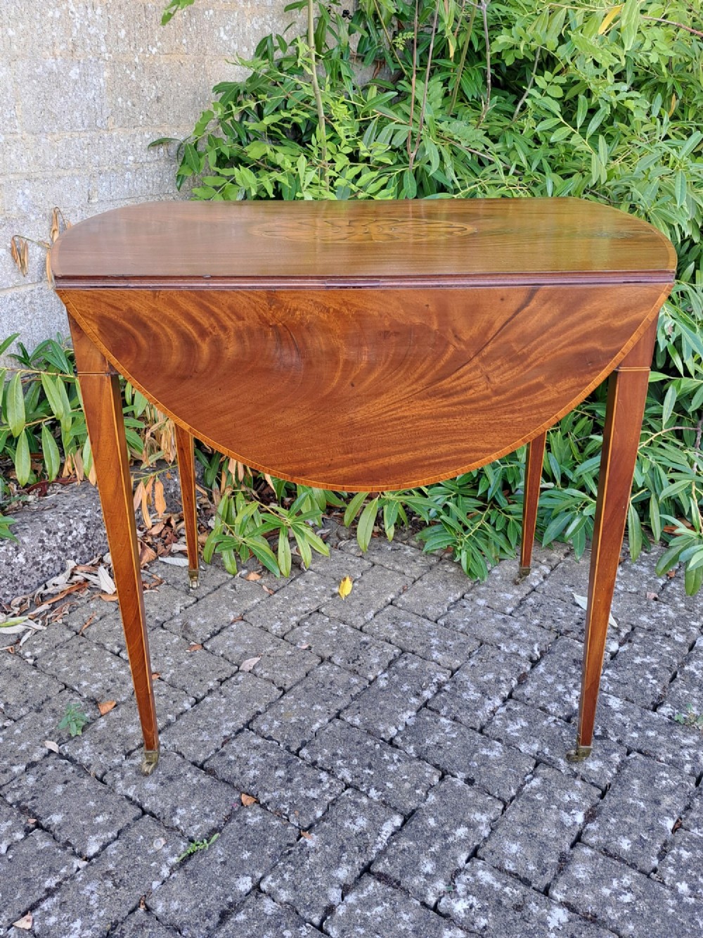 A George III mahogany drop-leaf Pembroke table featuring an oval satinwood shell inlay medallion, drawer with brass ring handles, and square tapered legs on brass castors. View V