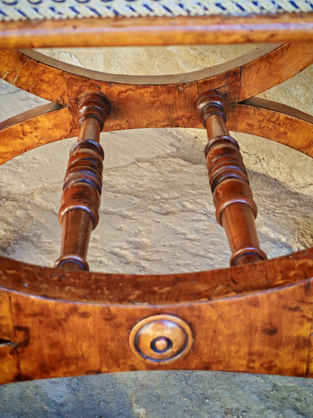 A mid-19th century X-frame stool crafted from figured burr maple, featuring a central turned stretcher and a neutral striped fabric upholstered seat. View III