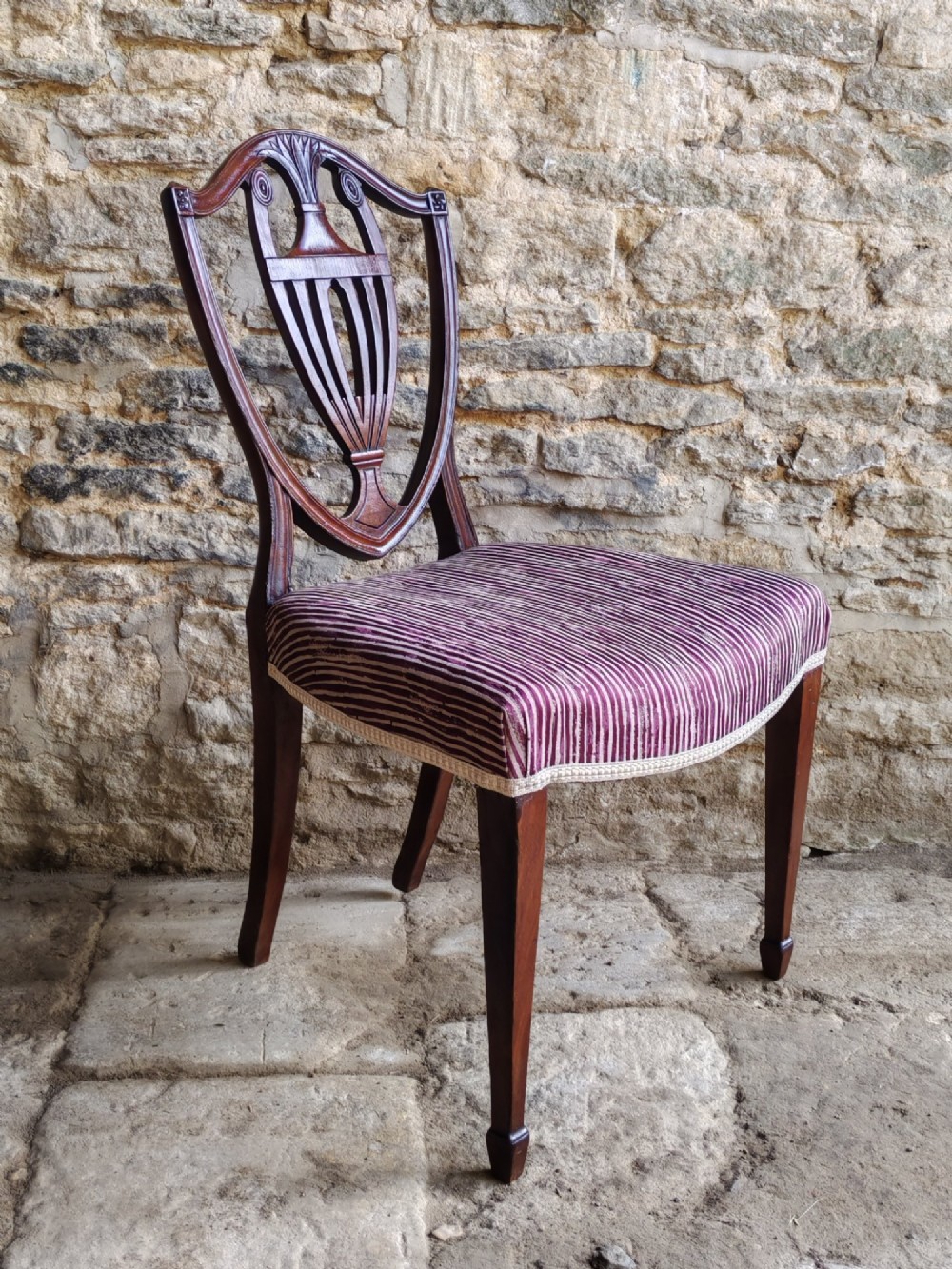 A set of six mahogany Hepplewhite dining chairs featuring carved shield backs with urn motifs and striped fabric upholstery. View III