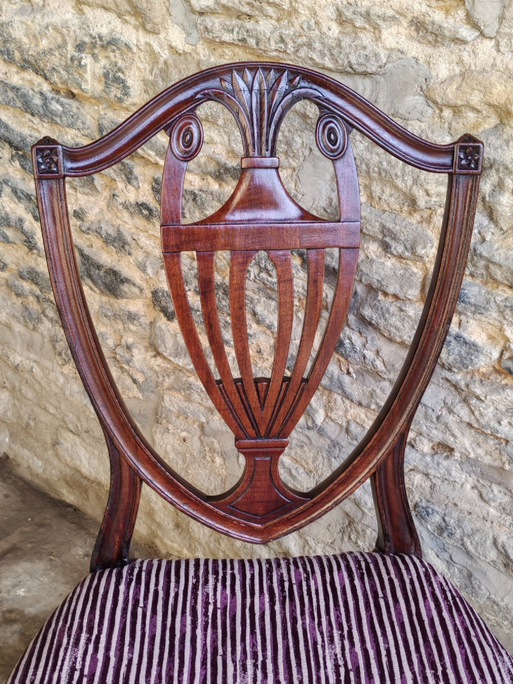 A set of six mahogany Hepplewhite dining chairs featuring carved shield backs with urn motifs and striped fabric upholstery. View IV