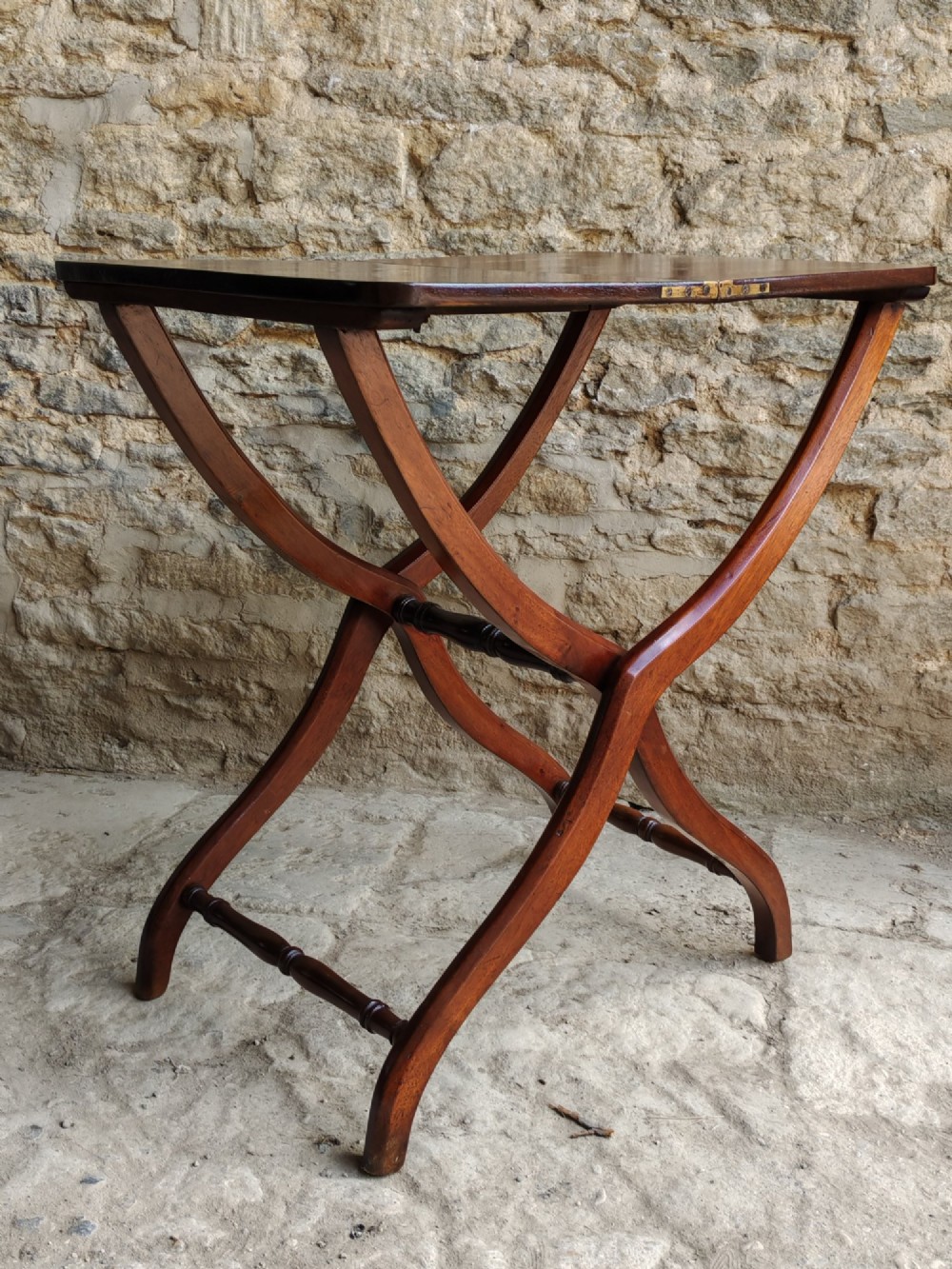 An Edwardian mahogany coaching table featuring a hinged folding rectangular top supported by curved X-frame legs and turned stretchers. View II