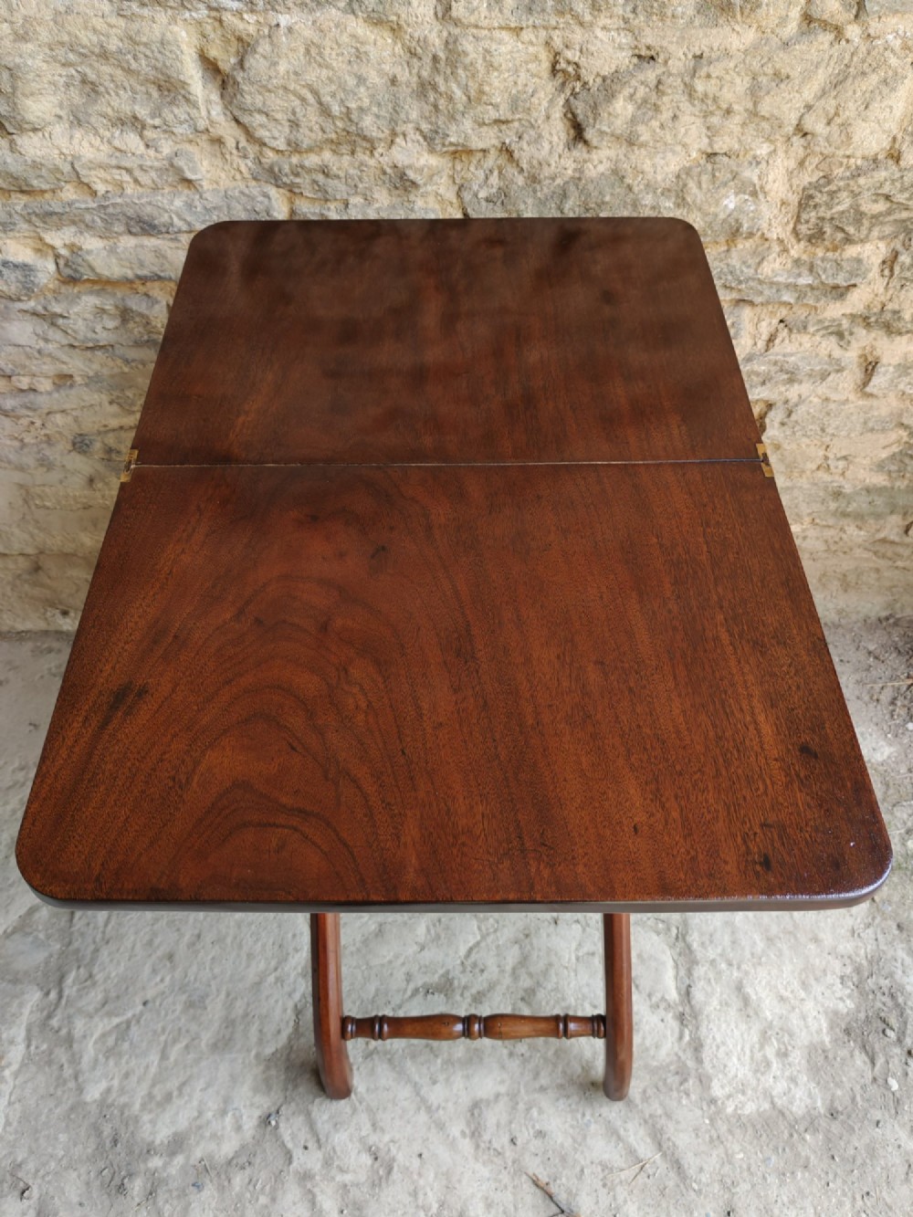 An Edwardian mahogany coaching table featuring a hinged folding rectangular top supported by curved X-frame legs and turned stretchers. View III