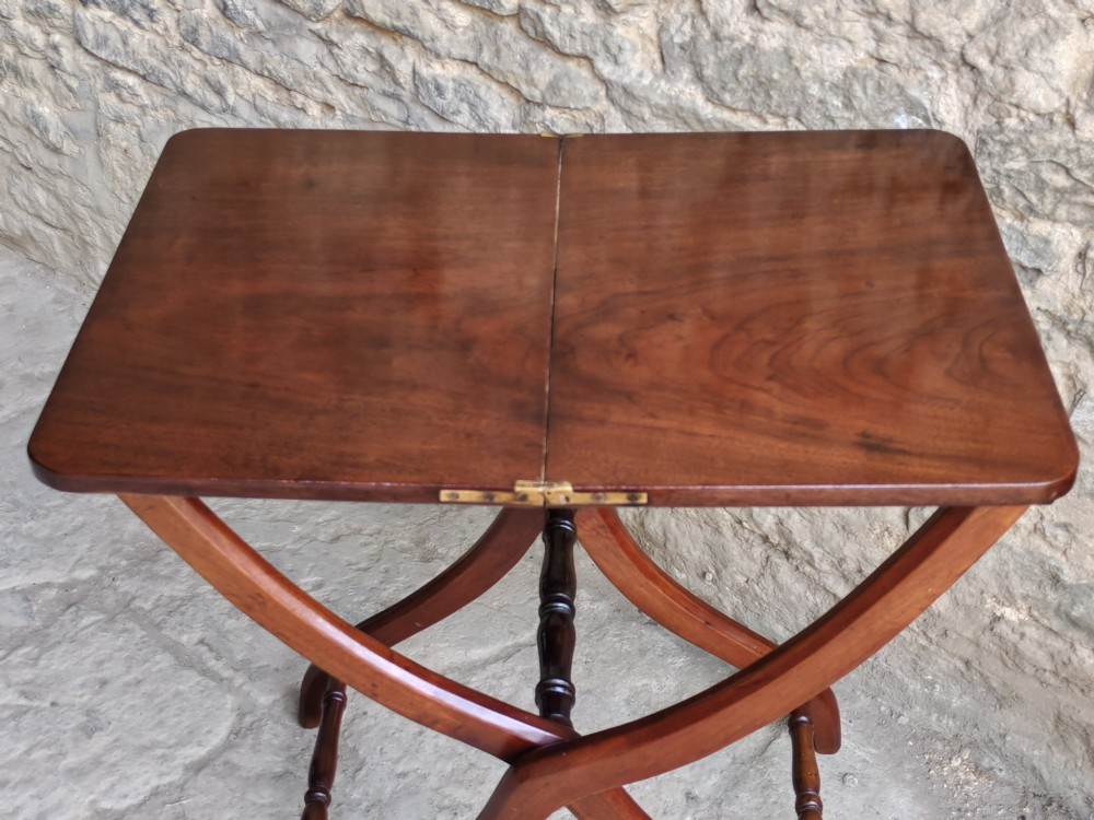 An Edwardian mahogany coaching table featuring a hinged folding rectangular top supported by curved X-frame legs and turned stretchers. View IV