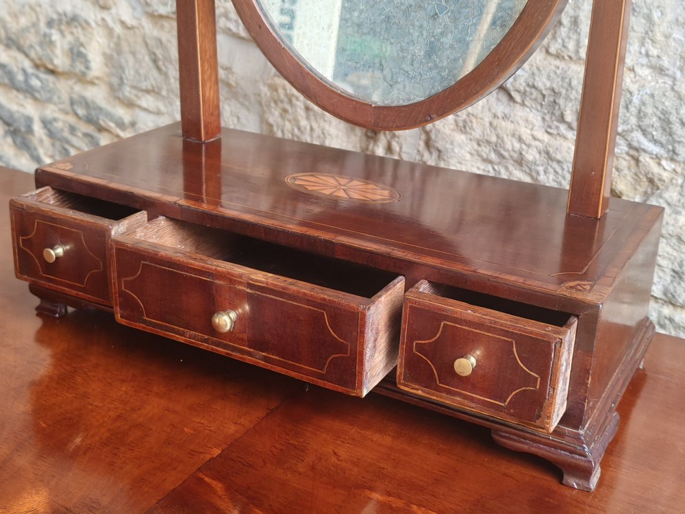 A Georgian mahogany dressing mirror featuring a shield-shaped swivel frame, bone finials, and an inlaid three-drawer box base. View VII