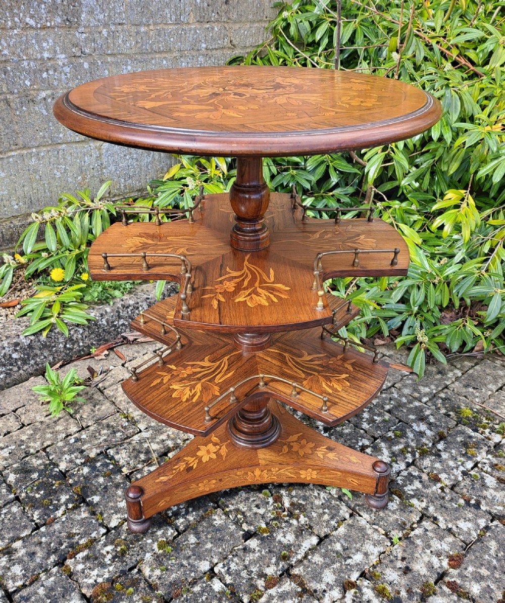 A circular Dutch marquetry revolving library table with floral wood inlays, tiered shelves featuring brass galleries, and a quadform pedestal base. View II