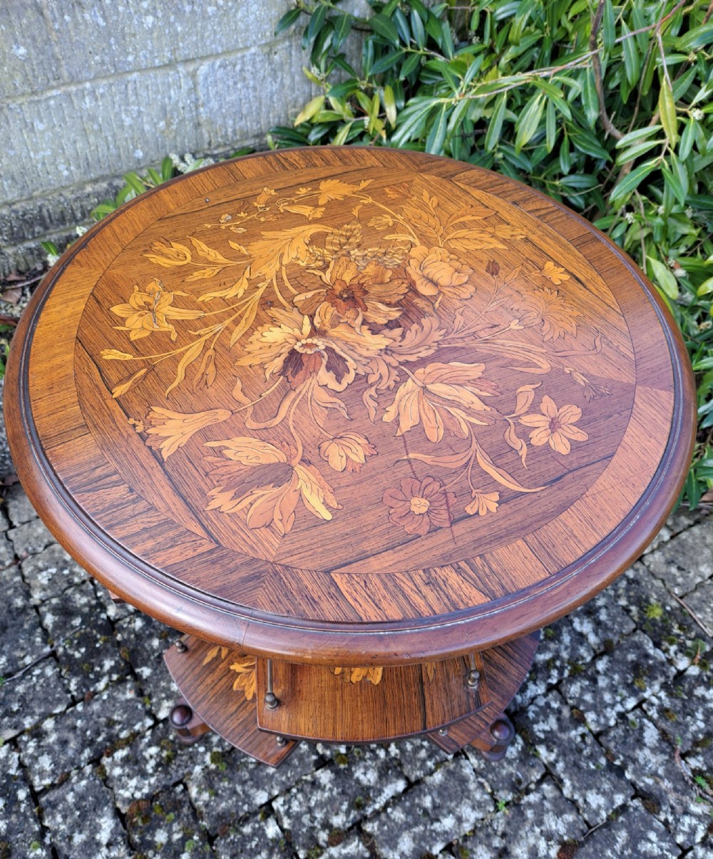 A circular Dutch marquetry revolving library table with floral wood inlays, tiered shelves featuring brass galleries, and a quadform pedestal base. View III
