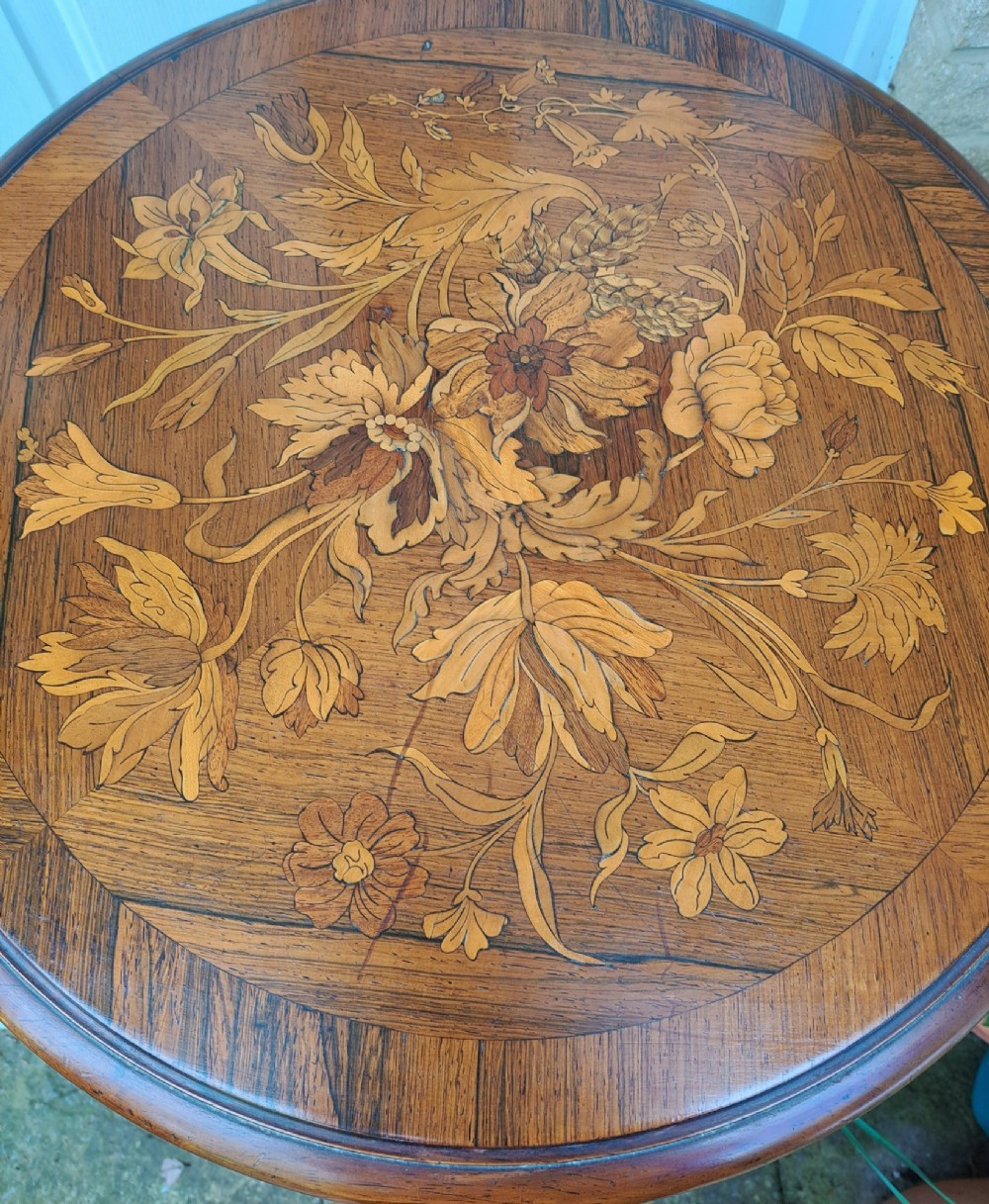 A circular Dutch marquetry revolving library table with floral wood inlays, tiered shelves featuring brass galleries, and a quadform pedestal base. View IV