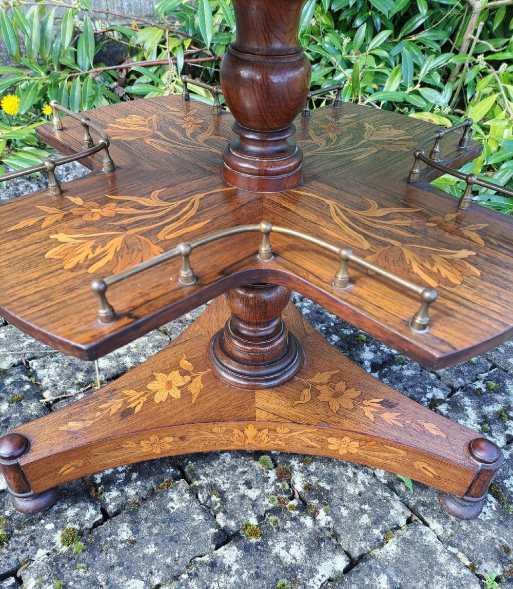 A circular Dutch marquetry revolving library table with floral wood inlays, tiered shelves featuring brass galleries, and a quadform pedestal base. View V