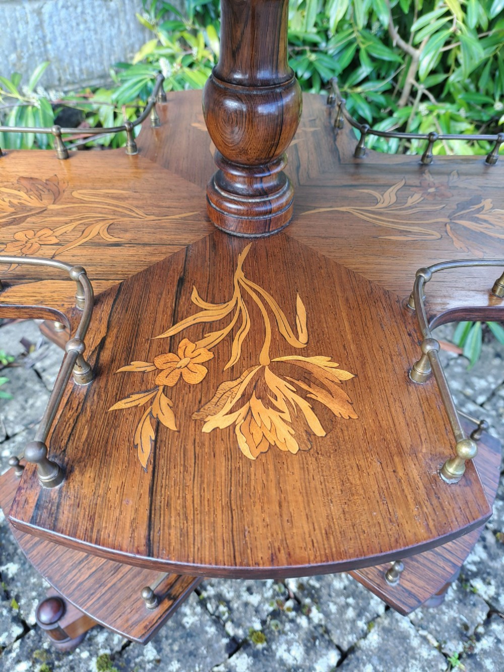 A circular Dutch marquetry revolving library table with floral wood inlays, tiered shelves featuring brass galleries, and a quadform pedestal base. View VI