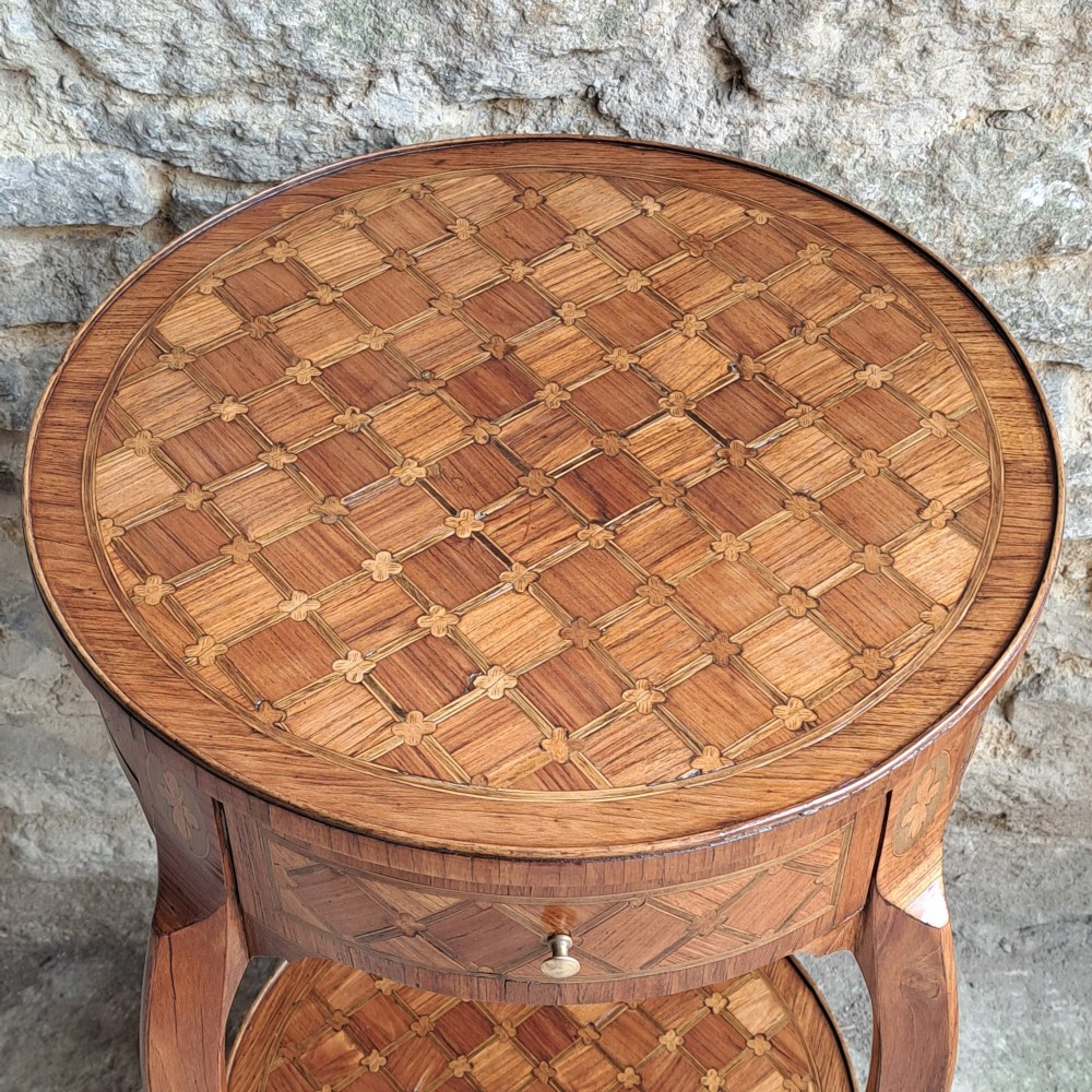 An antique circular French kingwood two-tier occasional table with geometric parquetry inlay, cabriole legs, and brass sabots. View III
