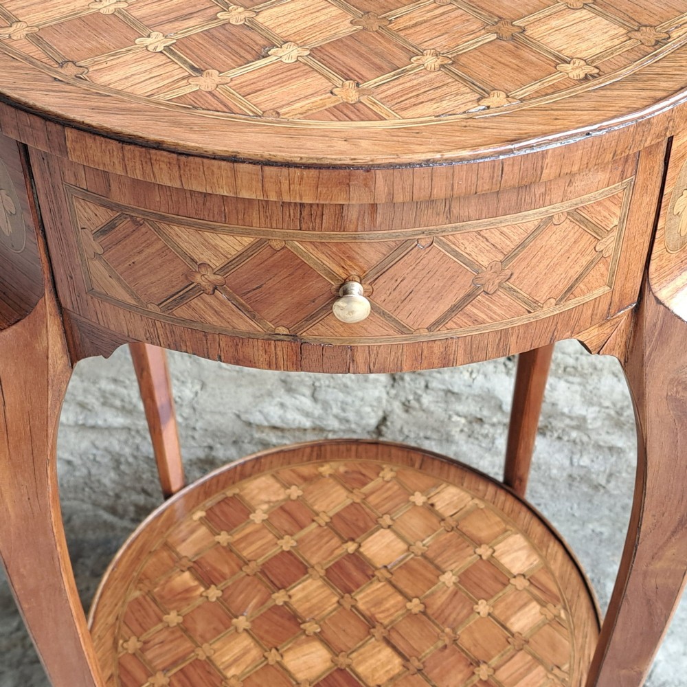 An antique circular French kingwood two-tier occasional table with geometric parquetry inlay, cabriole legs, and brass sabots. View V