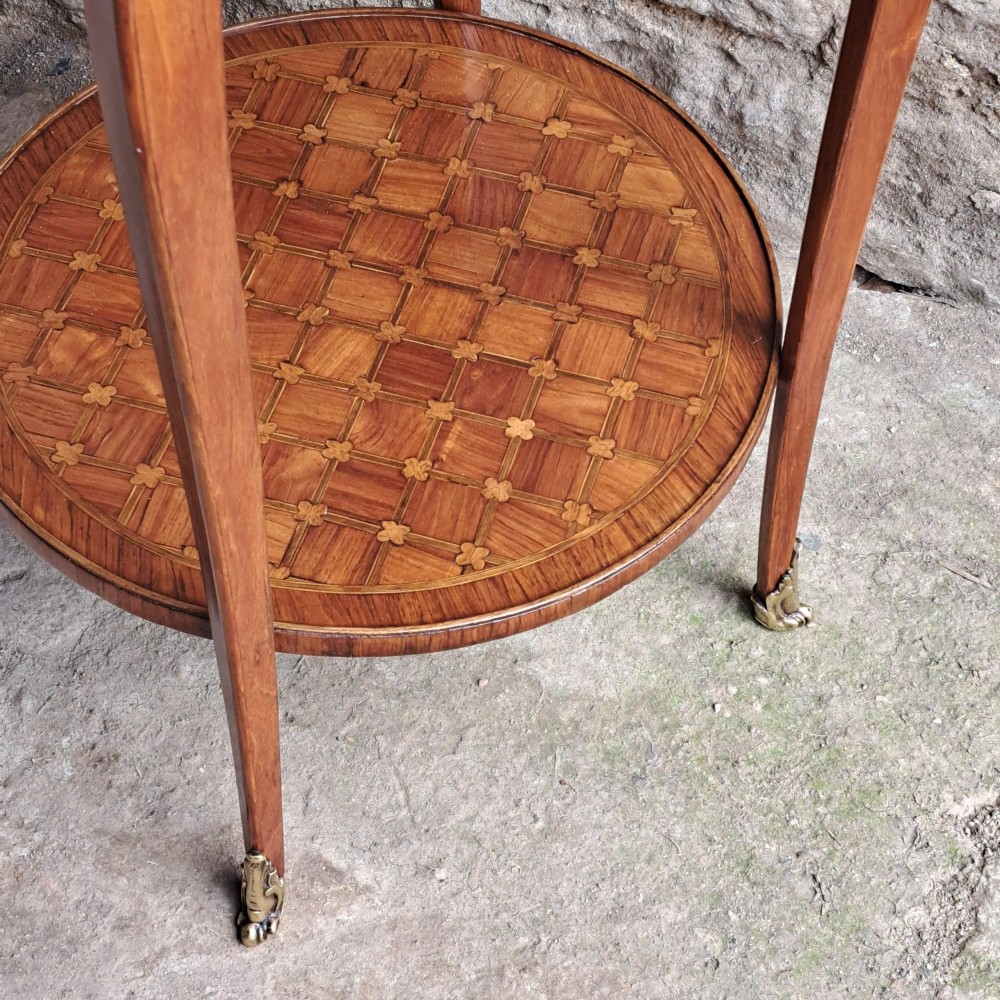 An antique circular French kingwood two-tier occasional table with geometric parquetry inlay, cabriole legs, and brass sabots. View VII