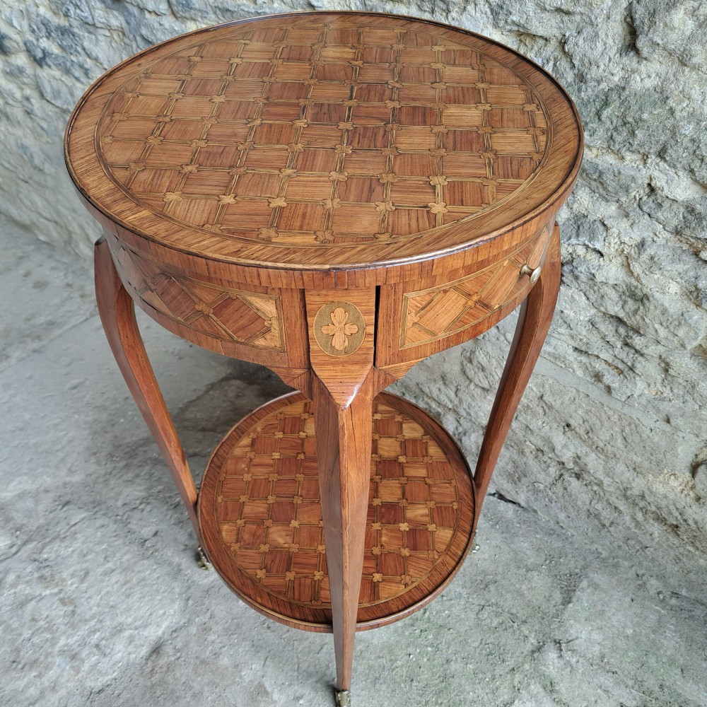 An antique circular French kingwood two-tier occasional table with geometric parquetry inlay, cabriole legs, and brass sabots. View IX