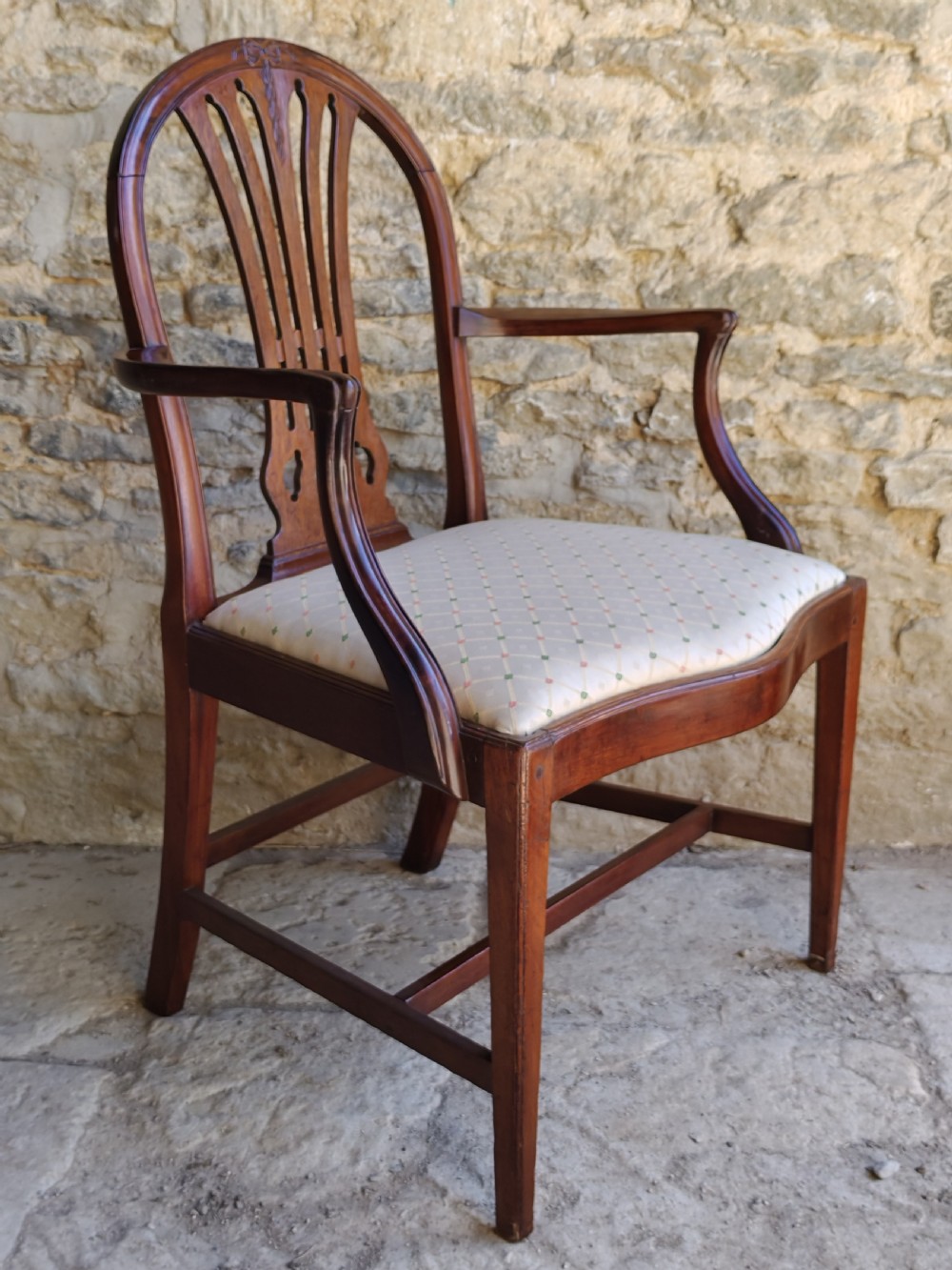 An 18th-century mahogany Hepplewhite carver armchair featuring an arched back with a pierced splat, sweeping armrests, an patterned upholstered seat, and square tapered legs. View II