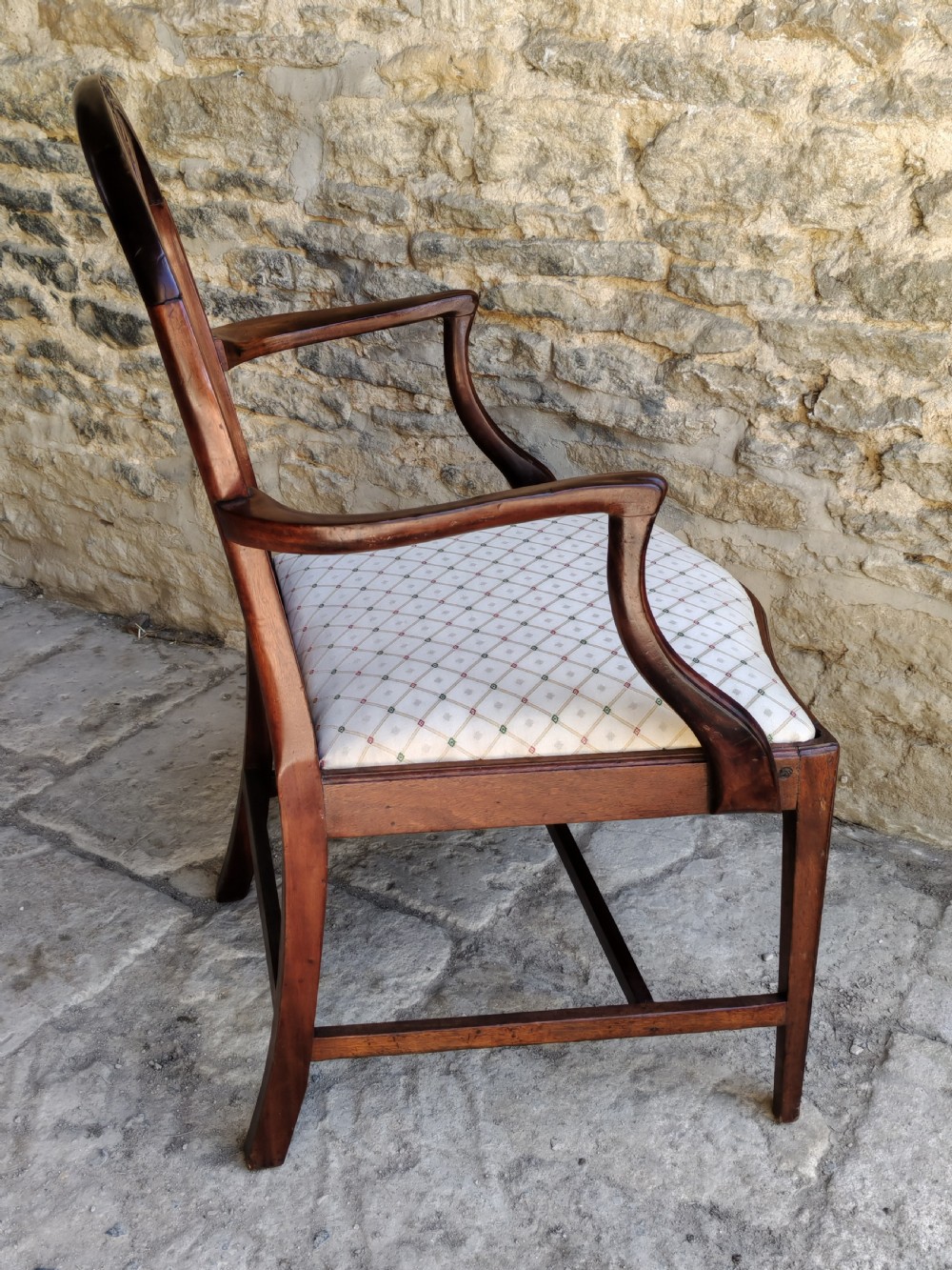 An 18th-century mahogany Hepplewhite carver armchair featuring an arched back with a pierced splat, sweeping armrests, an patterned upholstered seat, and square tapered legs. View V