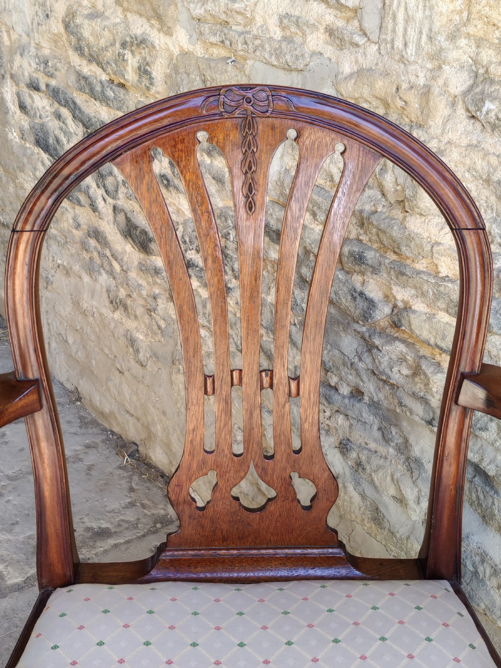 An 18th-century mahogany Hepplewhite carver armchair featuring an arched back with a pierced splat, sweeping armrests, an patterned upholstered seat, and square tapered legs. View VI