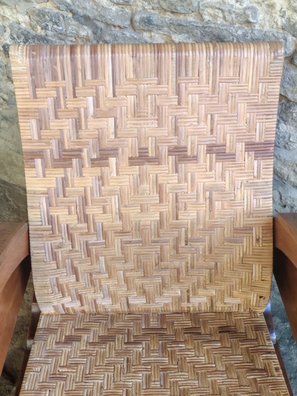 An Art Deco low-slung armchair featuring thick curved wooden armrests with circular cut-outs and a woven rattan seat and backrest. View VII