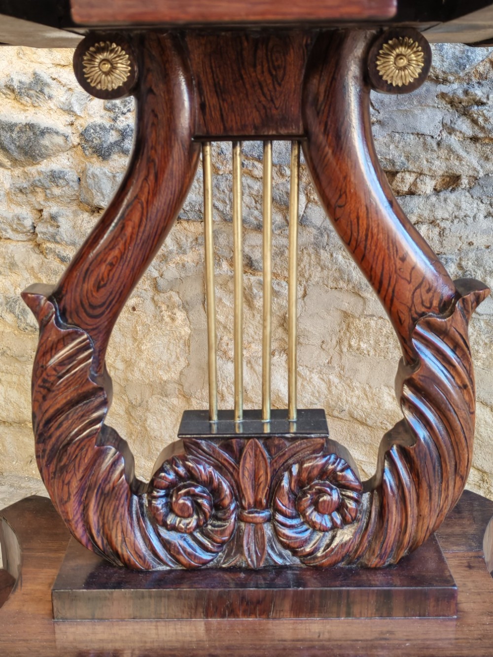 A Regency period rosewood tea table featuring a fold-over top, a central lyre-shaped support with brass rods, and a four-footed pedestal base with brass castors. View III