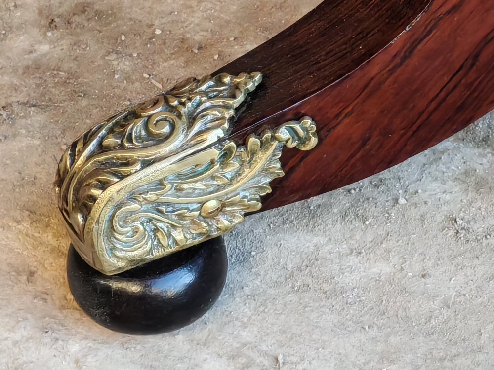 A Regency period rosewood tea table featuring a fold-over top, a central lyre-shaped support with brass rods, and a four-footed pedestal base with brass castors. View VIII