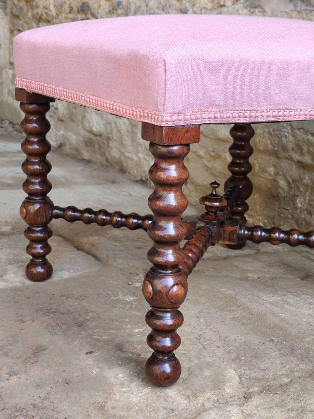 A Victorian rosewood stool featuring bobbin-turned legs, an X-shaped stretcher with a central finial, and a pink fabric upholstered seat. View III