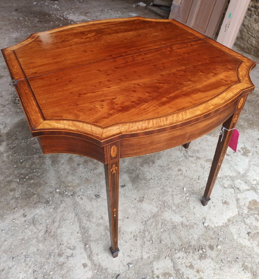 An antique late Victorian mahogany and satinwood fold-over tea table featuring a D-shaped top with satinwood crossbanding and tapered legs with floral marquetry. View II