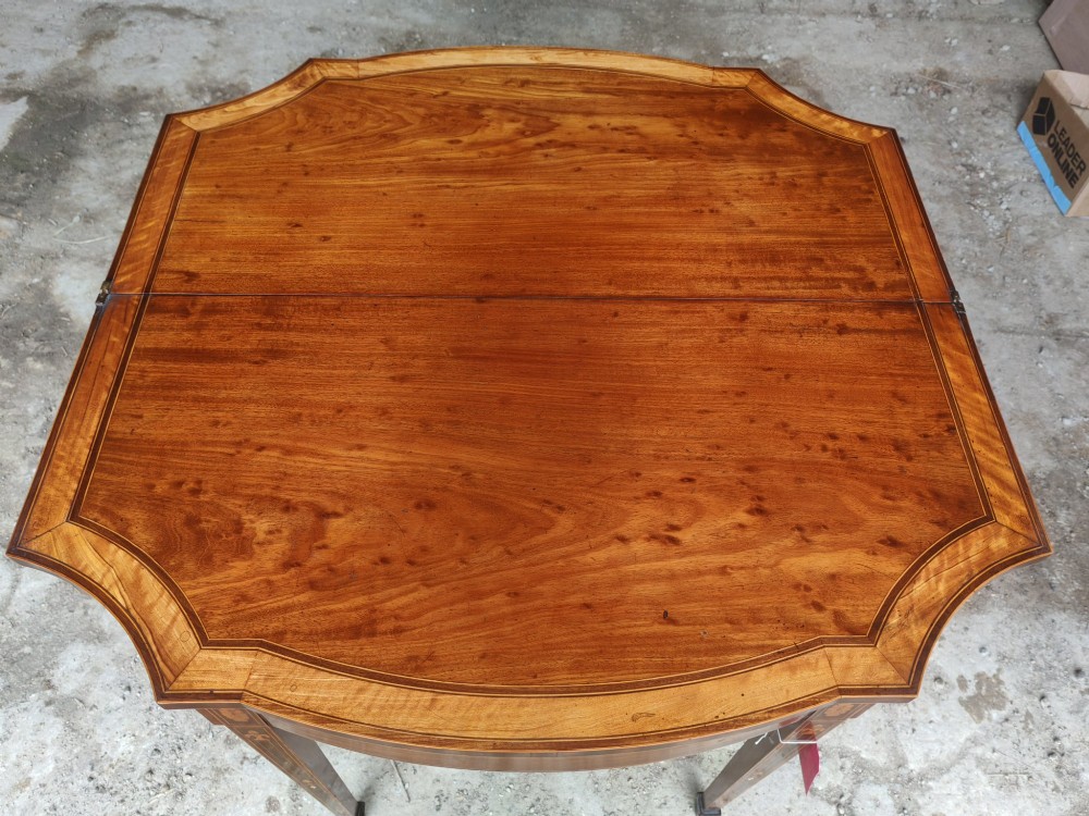 An antique late Victorian mahogany and satinwood fold-over tea table featuring a D-shaped top with satinwood crossbanding and tapered legs with floral marquetry. View III