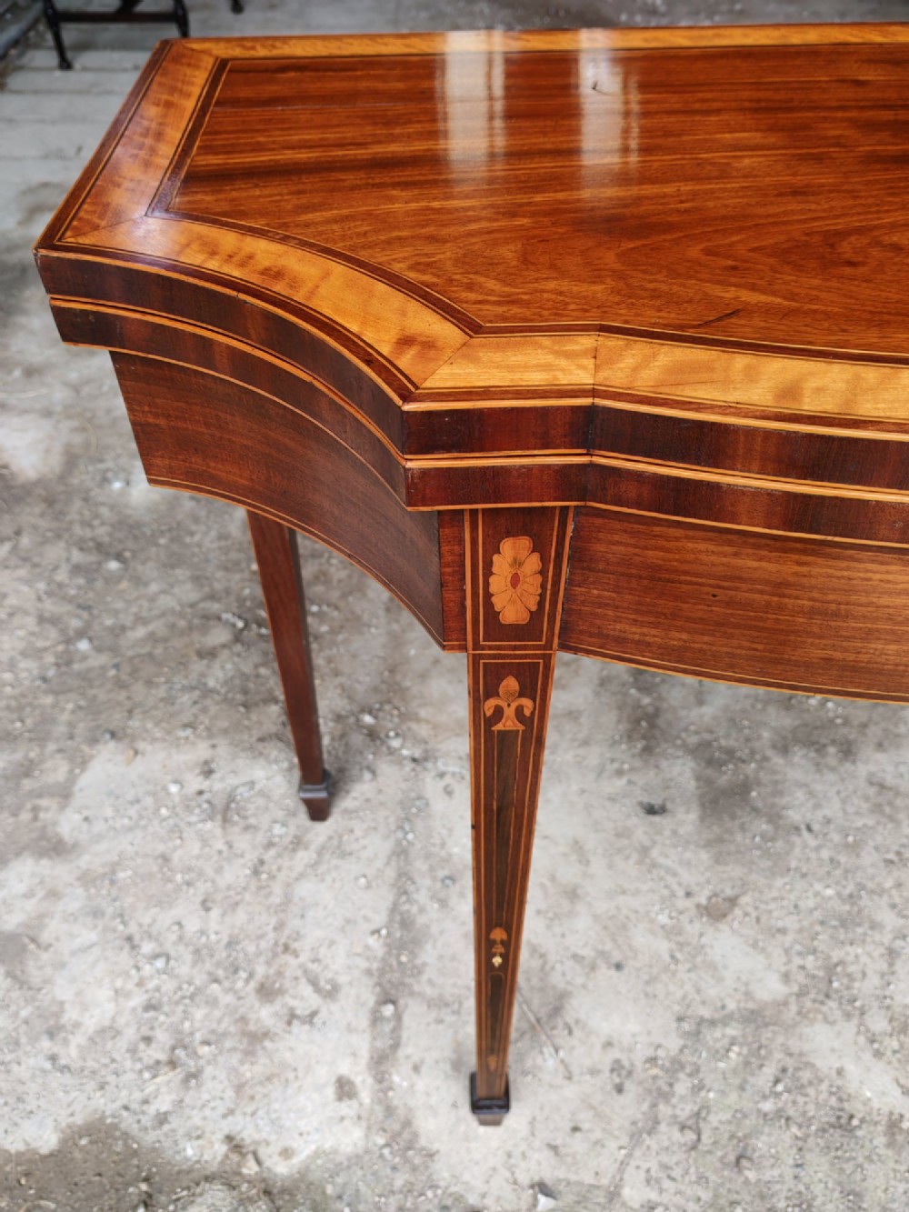 An antique late Victorian mahogany and satinwood fold-over tea table featuring a D-shaped top with satinwood crossbanding and tapered legs with floral marquetry. View IV