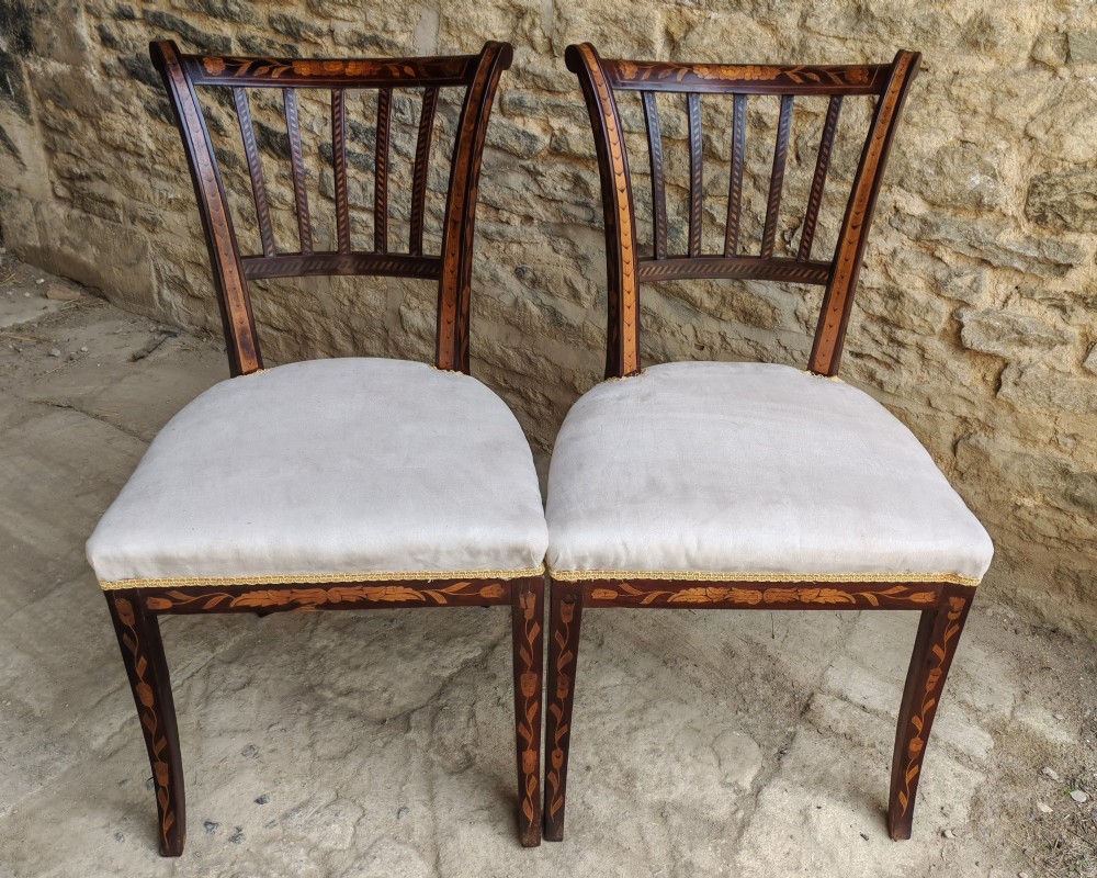 A pair of early 19th-century dark wood side chairs featuring floral marquetry inlay on the frames and light-coloured upholstered seats. View II