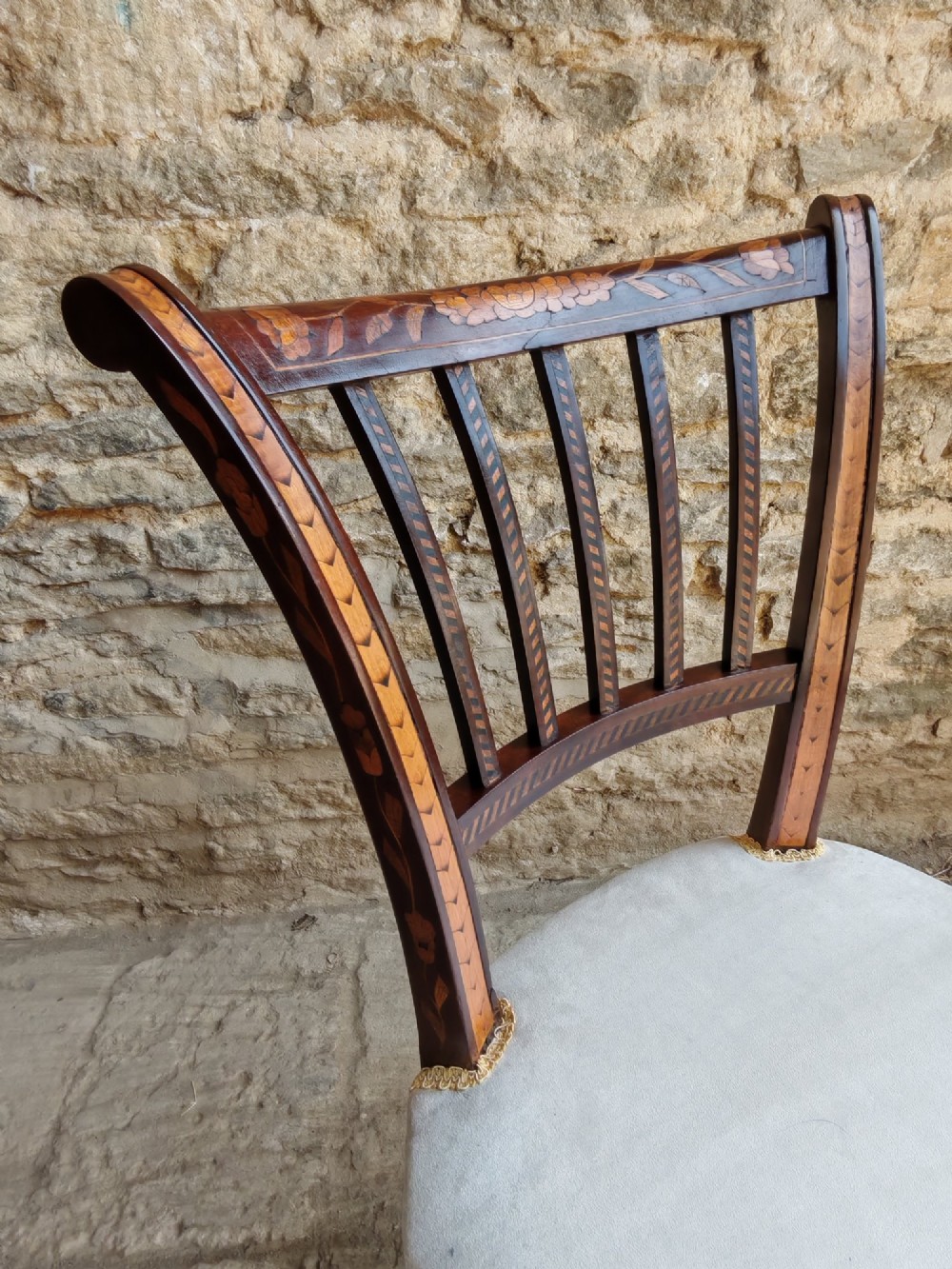 A pair of early 19th-century dark wood side chairs featuring floral marquetry inlay on the frames and light-coloured upholstered seats. View V