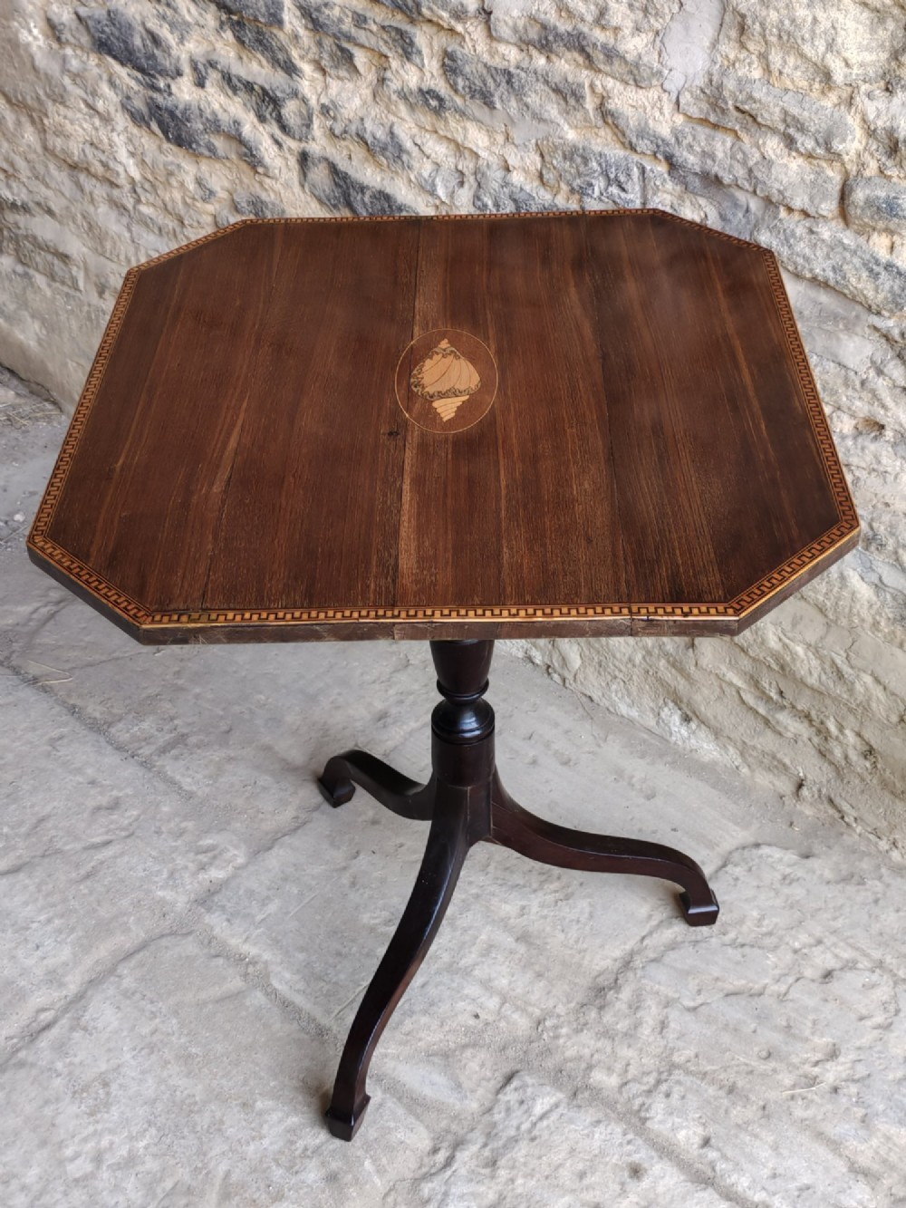 An octagonal dark mahogany Regency tilt-top table with central oval marquetry inlay, turned column, and splayed tripod legs. View II