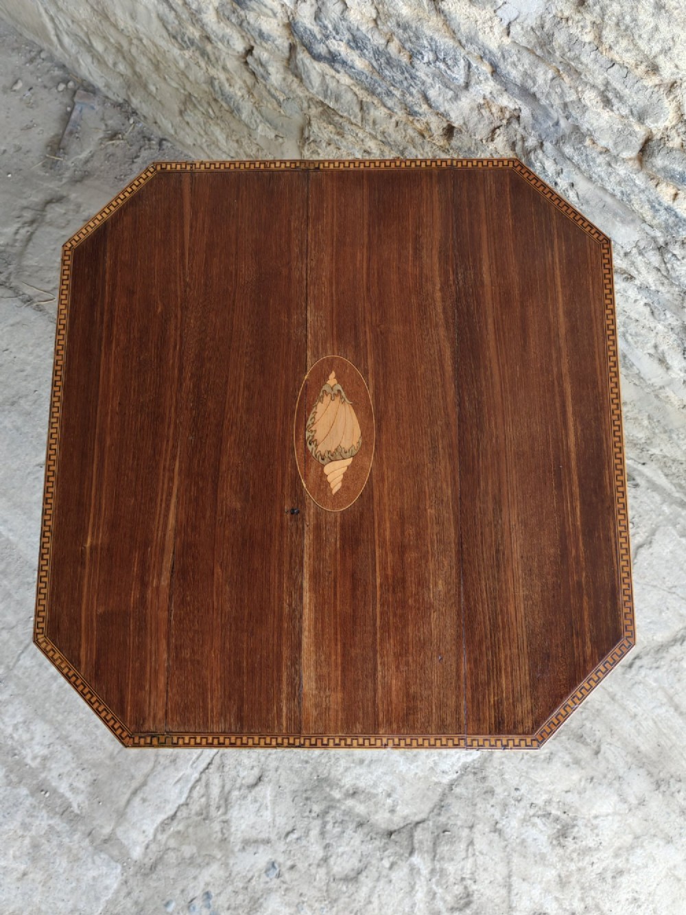 An octagonal dark mahogany Regency tilt-top table with central oval marquetry inlay, turned column, and splayed tripod legs. View III