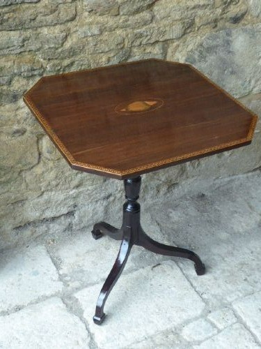 An octagonal dark mahogany Regency tilt-top table with central oval marquetry inlay, turned column, and splayed tripod legs.