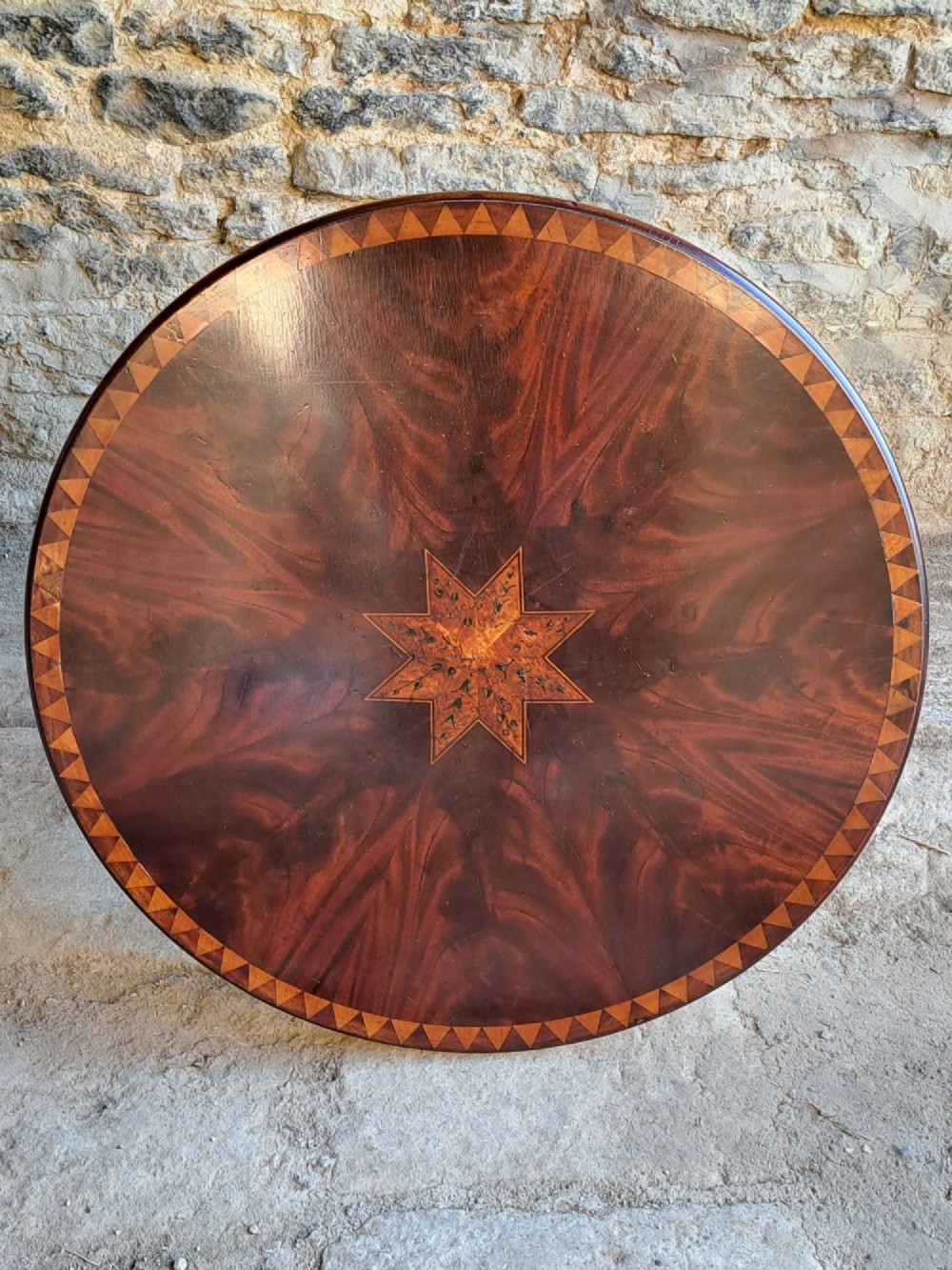 A circular mahogany occasional table featuring a central star inlay, geometric border, and sweeping sabre legs with brass castors. View II