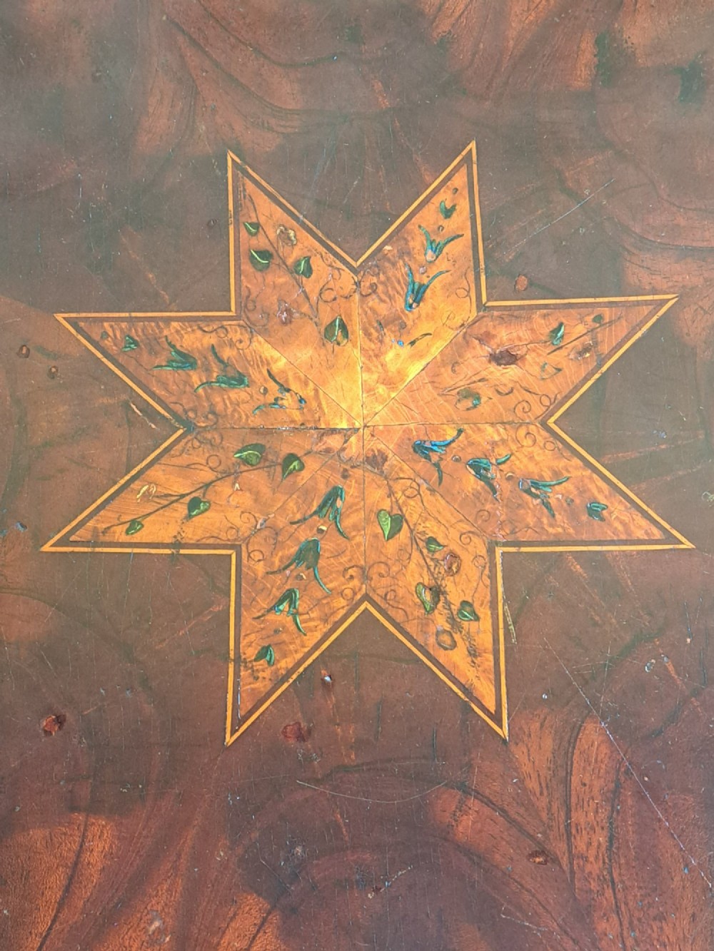 A circular mahogany occasional table featuring a central star inlay, geometric border, and sweeping sabre legs with brass castors. View III