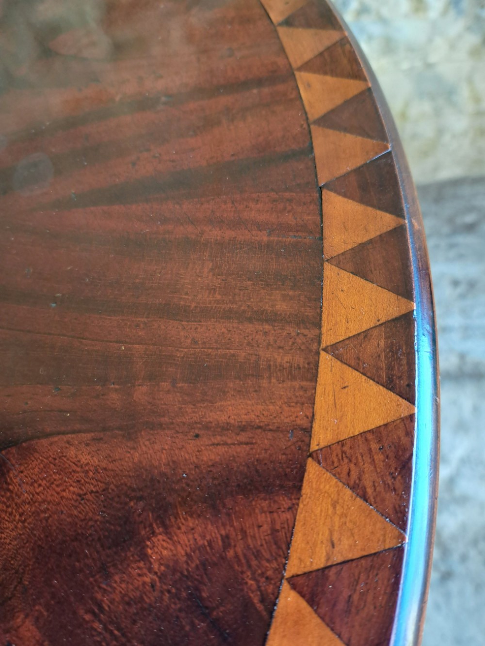 A circular mahogany occasional table featuring a central star inlay, geometric border, and sweeping sabre legs with brass castors. View IV